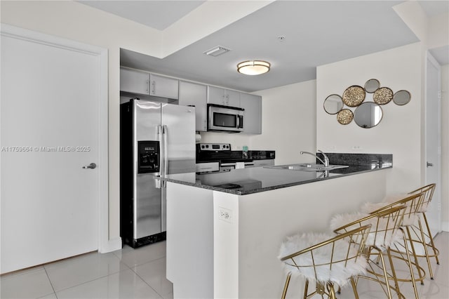 kitchen featuring visible vents, a breakfast bar, a peninsula, light tile patterned flooring, and stainless steel appliances