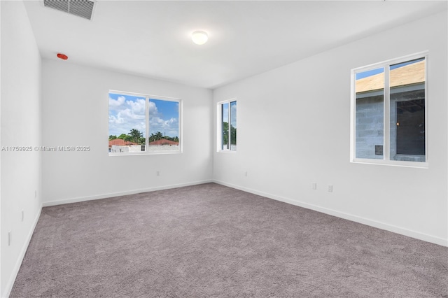 carpeted empty room featuring baseboards and visible vents