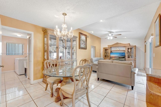 dining area featuring ceiling fan with notable chandelier, a textured ceiling, light tile patterned floors, baseboards, and washer / dryer