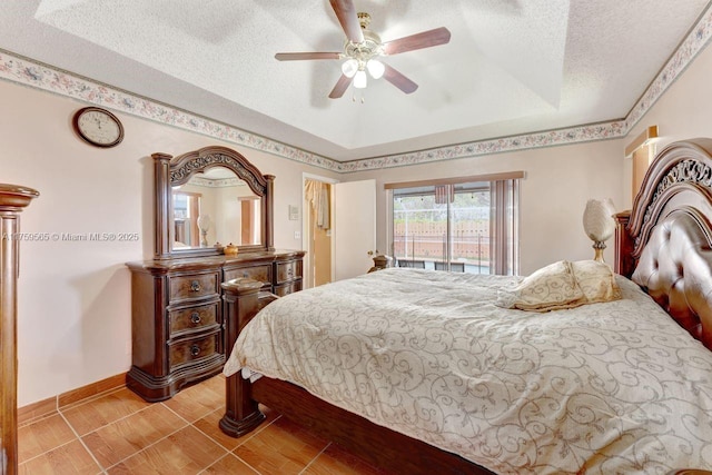 bedroom featuring ceiling fan, a raised ceiling, baseboards, and a textured ceiling