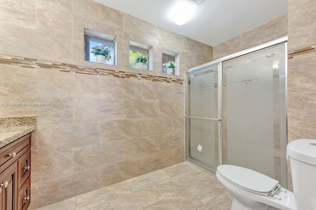 full bathroom with vanity, a shower stall, toilet, and tile walls