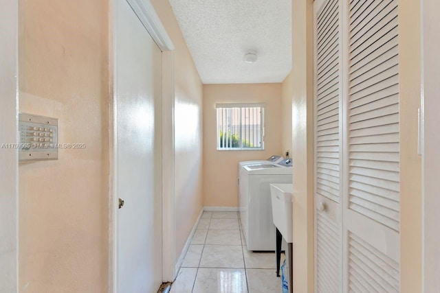 laundry room with baseboards, laundry area, light tile patterned flooring, separate washer and dryer, and a textured ceiling