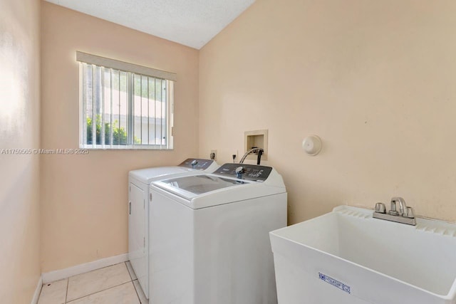 washroom with washing machine and clothes dryer, baseboards, laundry area, light tile patterned flooring, and a sink