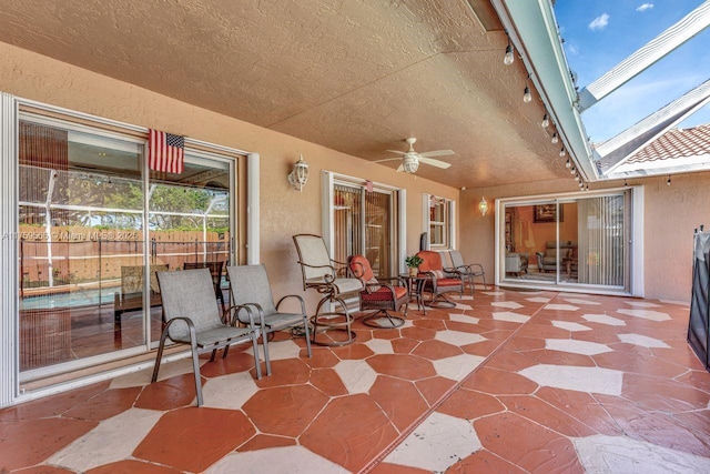 view of patio / terrace featuring glass enclosure and a ceiling fan