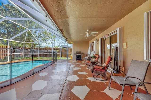 view of swimming pool featuring a fenced backyard, glass enclosure, a fenced in pool, ceiling fan, and a patio area