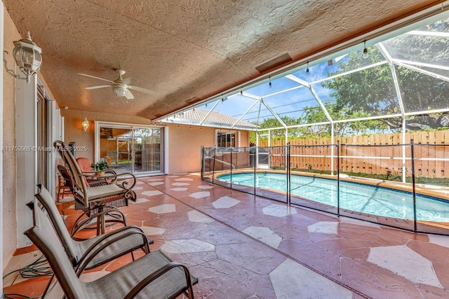 view of pool with a patio area, glass enclosure, a ceiling fan, and fence