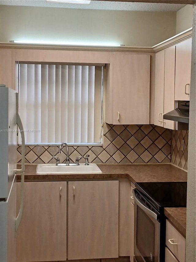 kitchen featuring a sink, decorative backsplash, stainless steel appliances, under cabinet range hood, and dark countertops