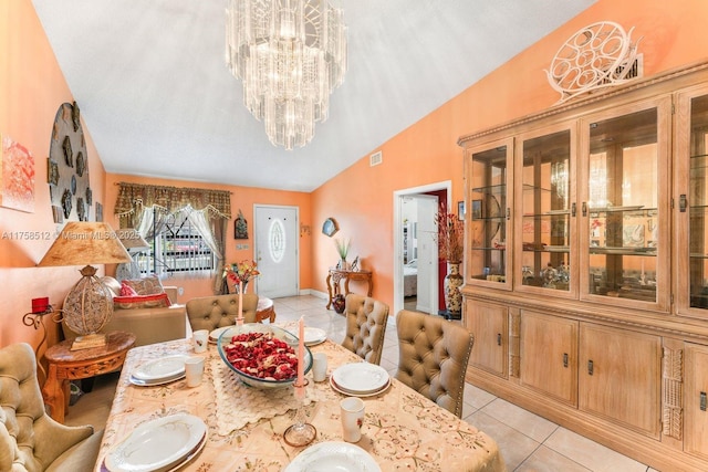 dining space with light tile patterned floors, visible vents, an inviting chandelier, and vaulted ceiling