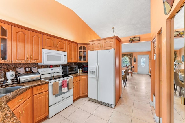 kitchen featuring light tile patterned floors, white appliances, and lofted ceiling