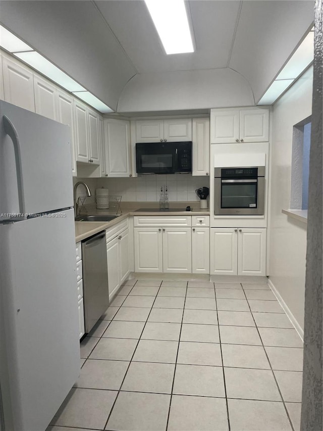 kitchen with black appliances, a sink, backsplash, white cabinetry, and light tile patterned floors