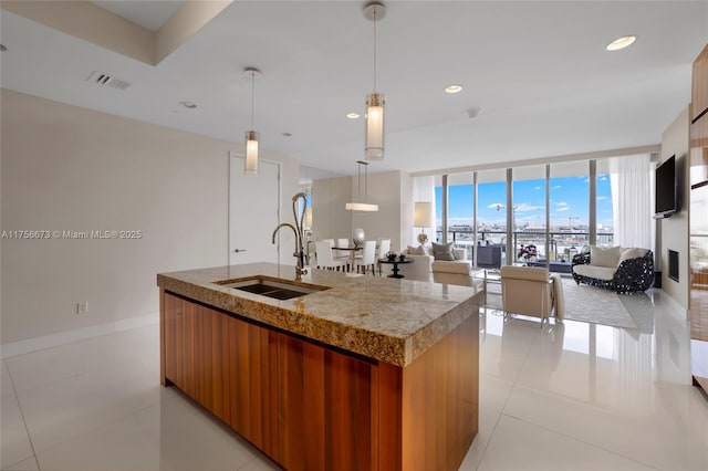 kitchen featuring open floor plan, a center island with sink, a wall of windows, modern cabinets, and a sink