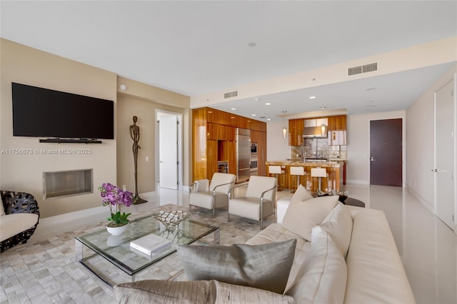 living room with recessed lighting, visible vents, baseboards, and a glass covered fireplace