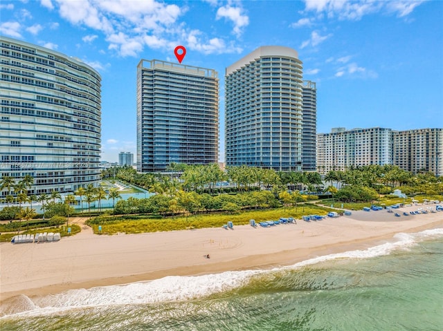 view of building exterior featuring a view of city, a beach view, and a water view