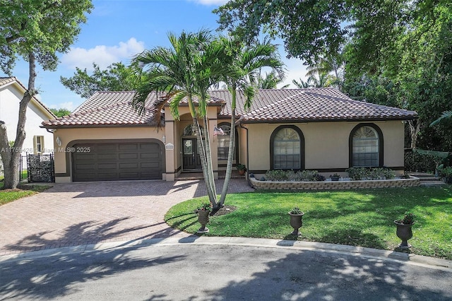 mediterranean / spanish-style house with stucco siding, a front lawn, a tile roof, decorative driveway, and an attached garage