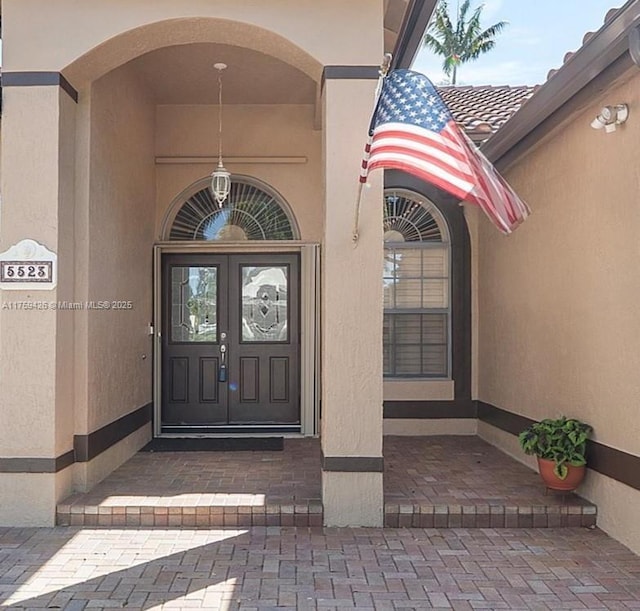 doorway to property featuring a tiled roof, french doors, and stucco siding