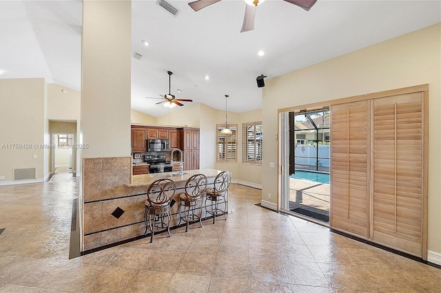 kitchen with stainless steel microwave, electric range, visible vents, and a breakfast bar