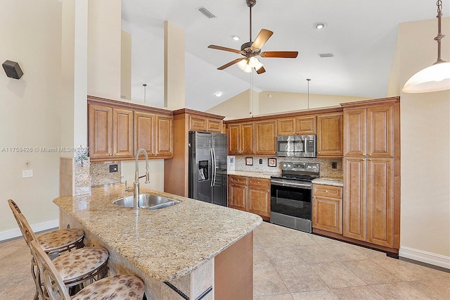 kitchen with brown cabinetry, visible vents, a peninsula, a sink, and stainless steel appliances