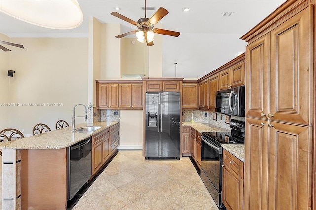 kitchen featuring visible vents, brown cabinets, black appliances, a sink, and a peninsula