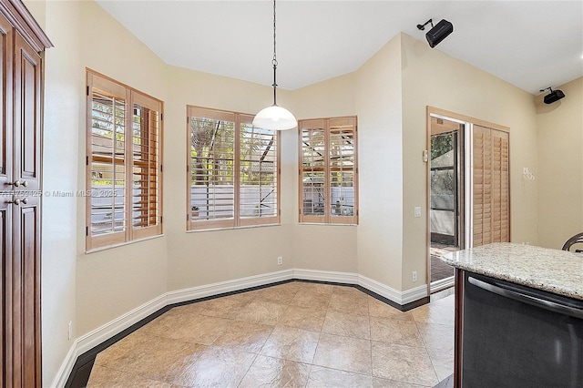 unfurnished dining area with lofted ceiling and baseboards