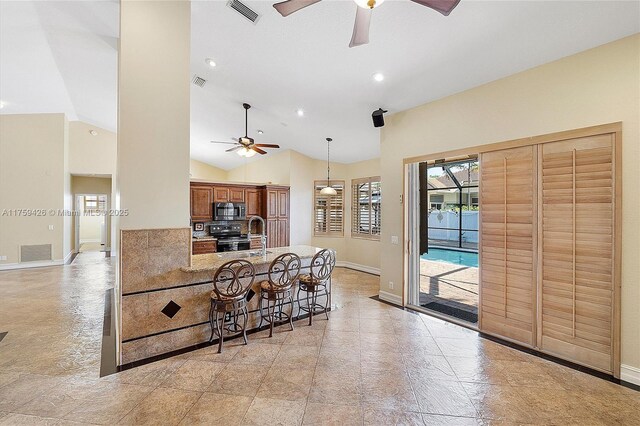 5523 NW 57th Ter, Coral Springs, FL 33067 - kitchen featuring stainless steel microwave, ceiling fan, a kitchen bar, black electric range, and vaulted ceiling