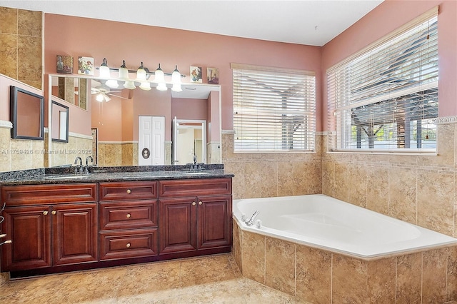 bathroom featuring a ceiling fan, a garden tub, double vanity, and a sink