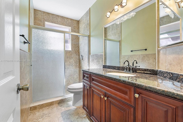 bathroom with a shower stall, tile walls, toilet, and a wealth of natural light