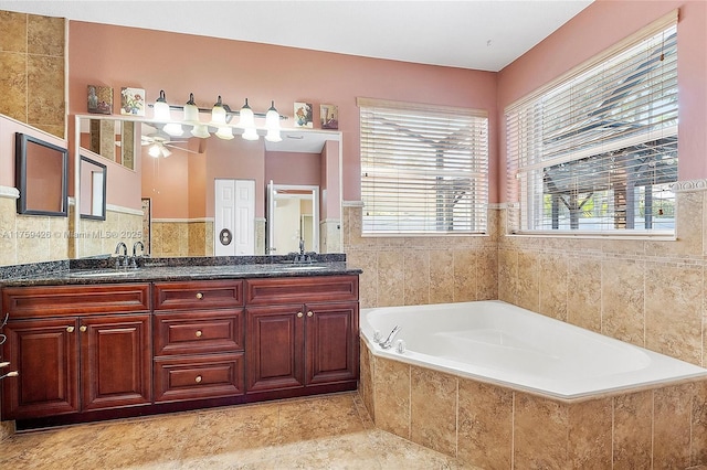 5523 NW 57th Ter, Coral Springs, FL 33067 - bathroom featuring tile walls, a bath, double vanity, ceiling fan, and wainscoting