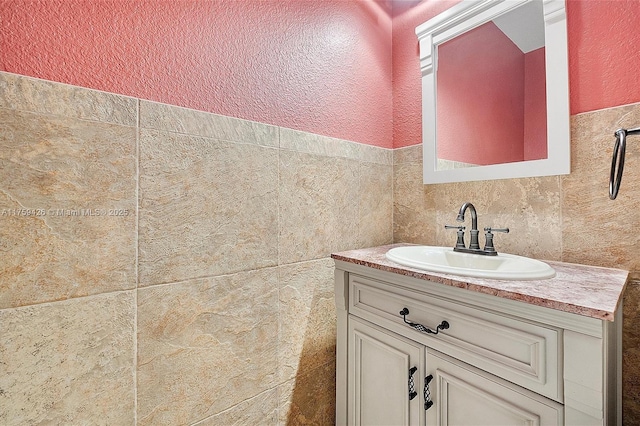 bathroom with tile walls, vanity, and a textured wall