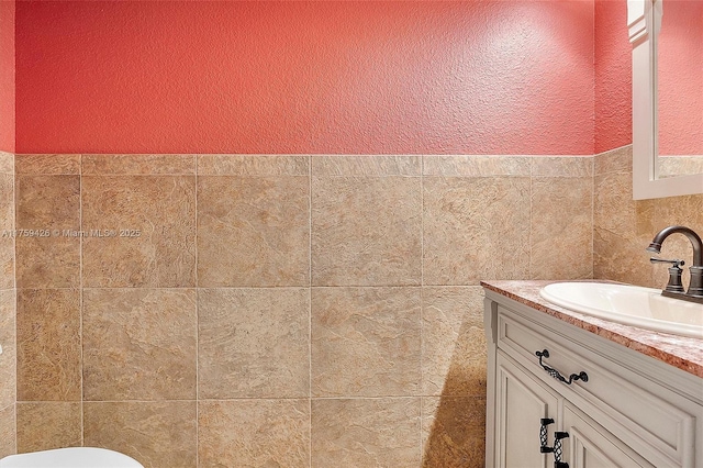 bathroom featuring toilet, vanity, and a textured wall