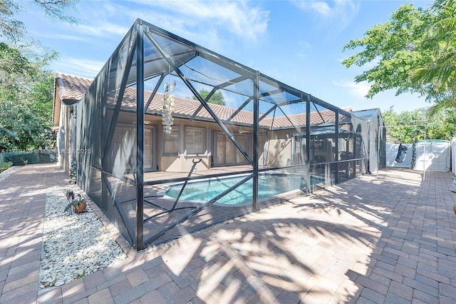 view of pool featuring glass enclosure, a patio, a fenced in pool, and fence