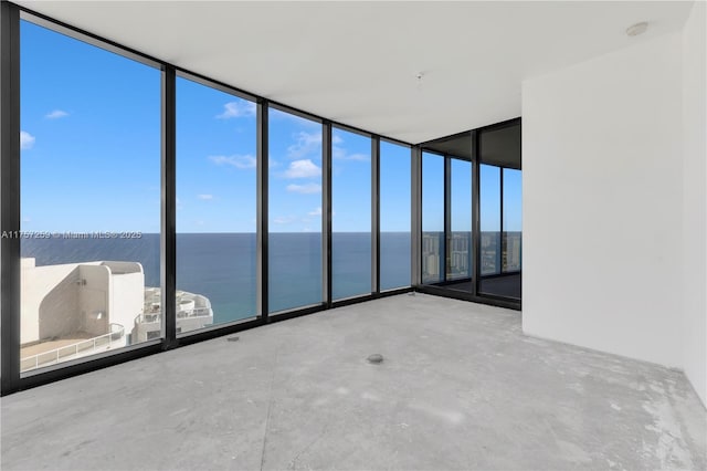 empty room featuring a wall of windows, a water view, and concrete flooring