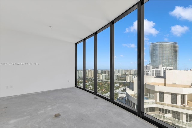 unfurnished room with concrete floors, expansive windows, and a city view