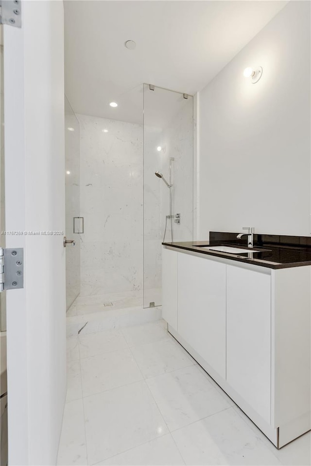 full bath with a sink and a marble finish shower