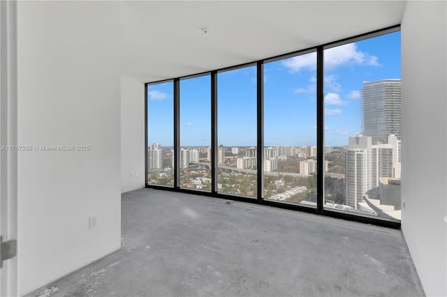 unfurnished room featuring a city view, floor to ceiling windows, and concrete floors