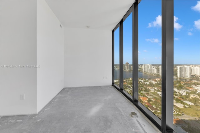 empty room with unfinished concrete floors, a view of city, and expansive windows