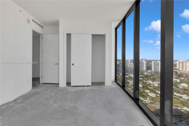 interior space with a wall of windows, a view of city, and concrete flooring