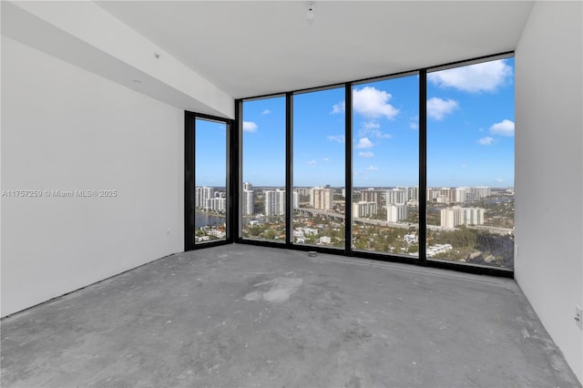 spare room with concrete floors, a city view, and floor to ceiling windows