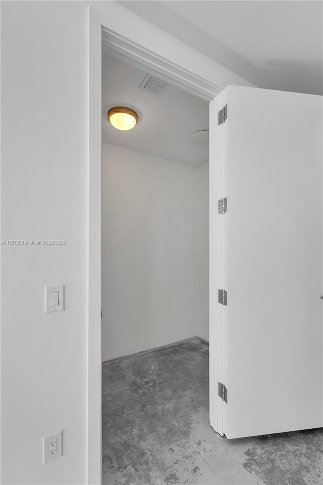 hall with unfinished concrete flooring and visible vents