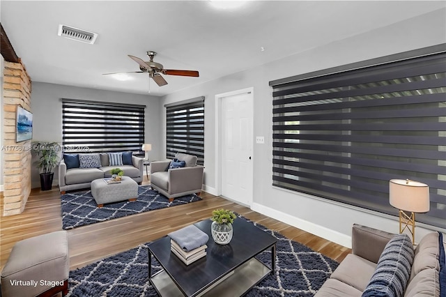 living area with visible vents, ceiling fan, baseboards, and wood finished floors