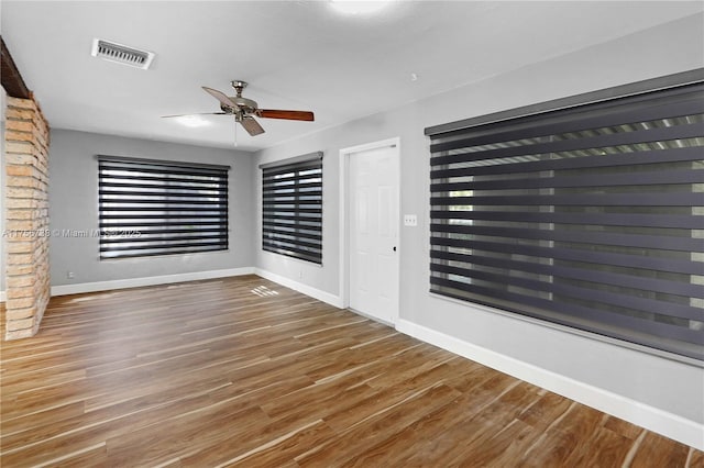 empty room with visible vents, baseboards, and wood finished floors