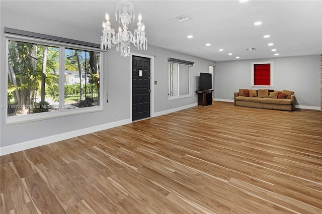 unfurnished living room with light wood finished floors, visible vents, baseboards, recessed lighting, and an inviting chandelier