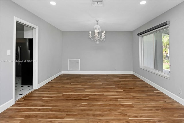 unfurnished room with wood finished floors, visible vents, and baseboards