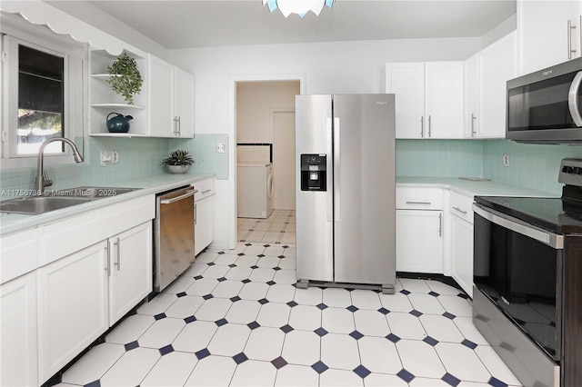 kitchen featuring washer / dryer, light floors, appliances with stainless steel finishes, and a sink