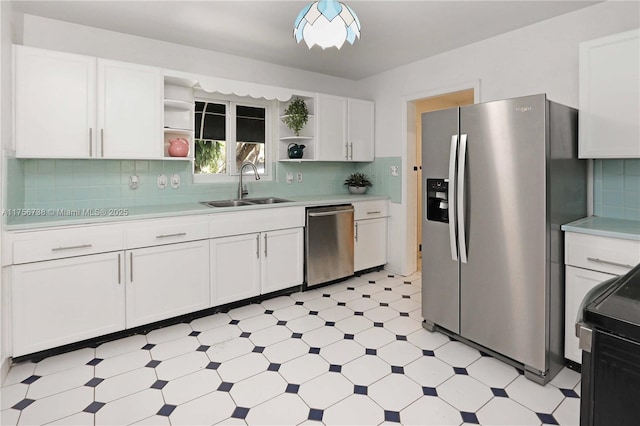 kitchen featuring light floors, open shelves, a sink, stainless steel appliances, and light countertops