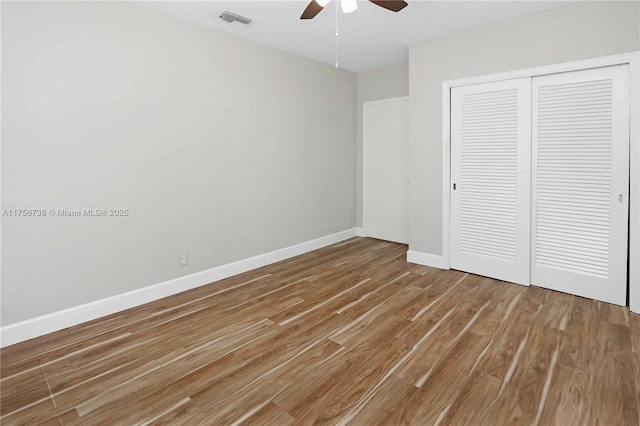 unfurnished bedroom featuring a closet, visible vents, baseboards, and wood finished floors