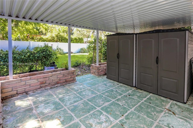 view of patio / terrace featuring an outdoor structure, a fenced backyard, and a shed