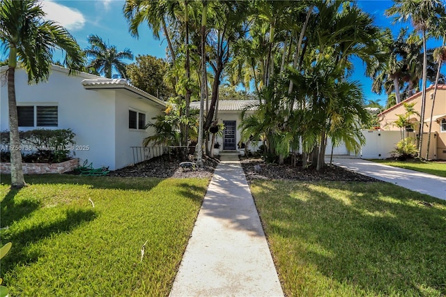 view of front of property with stucco siding, a front yard, and fence