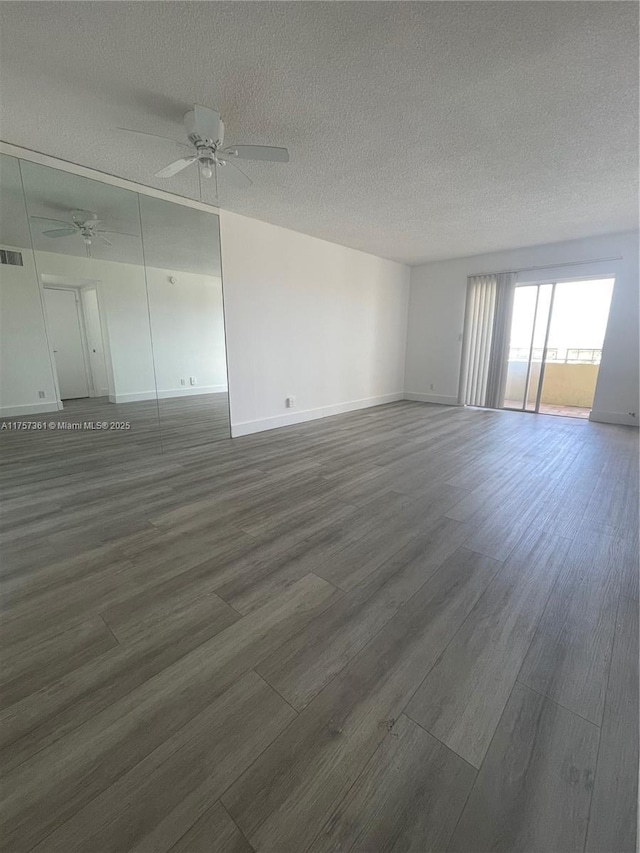 spare room with a ceiling fan, dark wood-style floors, visible vents, and a textured ceiling