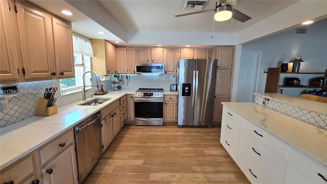 kitchen with light stone countertops, visible vents, appliances with stainless steel finishes, and a sink