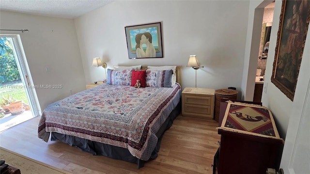 bedroom featuring a textured ceiling, access to outside, and light wood finished floors